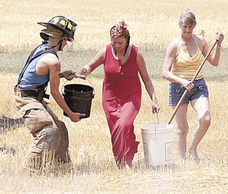 Friends and neighbors help firefighters control a large field fire Wednesday in the 62000 block of Lutz Road.