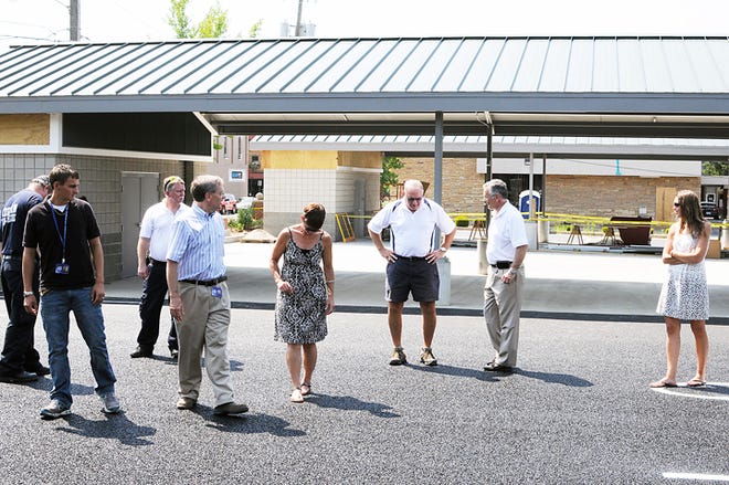 Adrian city employees inspect the new porous pavement at the new farmers market shelter in the north Toledo Street parking lot Friday, seconds after more than 9,000 gallons of water were sprayed on it from an Adrian fire engine to demonstrate its porous quality. During the demonstration no water pooled up on the pavement. It was all absorbed into the pavement immediately.