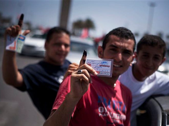 Libyan men hold their elections ID cards while celebrating election day in Tripoli, Libya, Saturday, July 7, 2012. Jubilant Libyan voters marked a major step toward democracy after decades of erratic one-man rule, casting their ballots Saturday in the first parliamentary election after last year's overthrow and killing of longtime leader Moammar Gadhafi. AP Photo/Manu Brabo)