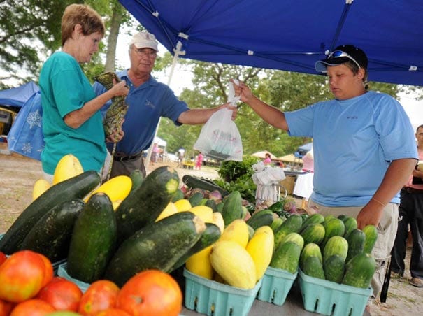 Joy and George Ball buy produce from Kyle Rommell at his produce stand at the Poplar Grove Farmers Market in Wilmington.
