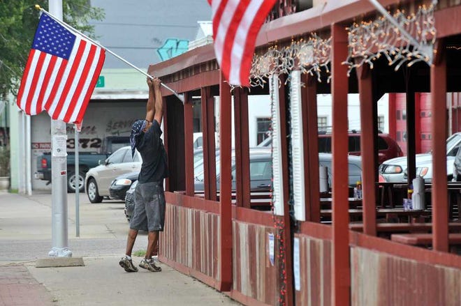 MICHAEL SCHUMACHER / AMARILLO GLOBE-NEWS  Shaman Hunter raises the American flag at Smokey Joe's, 2903 S.W. Sixth Ave.