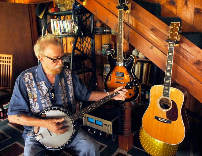 Vic Waters picks at a banjo at his home overlooking the Sapelo River. Waters has overcome cancer, joking "I'm still here."