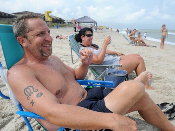 Erik Smith, joined by his nonsmoking wife, Amy, enjoys a cigarette while spending the day at Carolina Beach on Tuesday. Smith, who lives in Reidsville, said a smoking ban would impact his decision to visit Carolina Beach in the future.