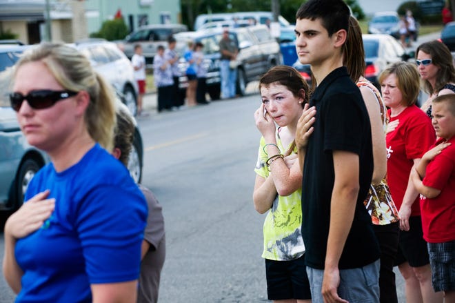 Kylie Rice, center, reacts as the funeral procession for siblings Alexandra Anderson and Brayden Anderson moves through downtown Ashland. As the procession passed, residents put their hands on their hearts and stood in silence. Alexandra, 13, and Brayden, 8, were electrocuted while swimming off their family's dock at the Lake of the Ozarks on July 4.