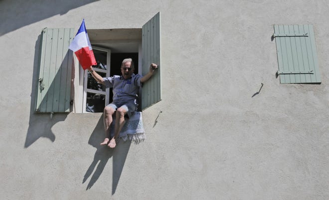 A spectator waves the French flag as the pack passes during the 12th stage of the Tour de France cycling race over 226 kilometers (140.5 miles) with start in Saint-Jean-de-Maurienne and finish in Annonay, France, Friday. (AP Photo/Christophe Ena)