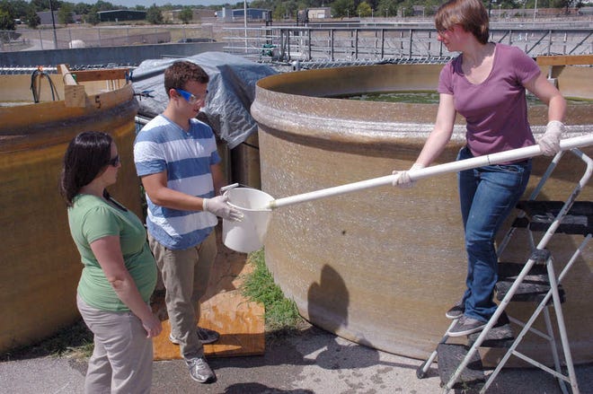 Belinda Sturm, assistant professor of civil, environmental and architectural engineering, left, supervises KU students Luigi Basalo and Marie-Odile Fortier as they collect a water sample from a 2,500-gallon holding tank where algae is being grown.