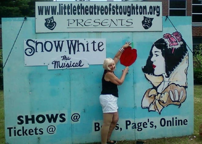 Jan Jones puts up a poisonous apple on a “Snow White” billboard for an upcoming Little Theatre of Stoughton performance.