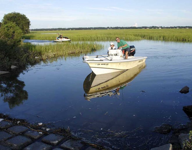 Terry.Dickson@jacksonville.com Clement Cullens and his mother, Ann Cullens, guide their boat to the Village Creek boat ramp at St. Simons Island on Monday. P and M Cedar Products plans to build a restaurant and single-family residences on the property it owns near the ramp.