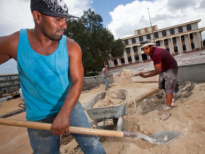 Construction workers Pablo Sosa, left and Ednilson Rocha, right, shovel sand for what will be used as a base for pavers in the Citizens' Circle and Linear Park construction Thursday afternoon. Ocala City Hall has a new address, because the city has closed off a piece of Osceola Avenue in front of the building for the Linear Park. The city is now using the back door as the front door. And the citizens circle will now be at the new back door instead of the old front door.