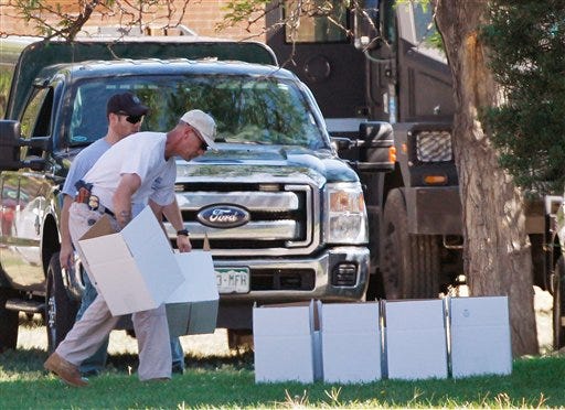 An ATF agent arranges boxes for evidence in front of the apartment of James Holmes in Aurora, Colo., Saturday, July 21, 2012. Federal authorities detonated one small explosive and disarmed another inside Holmes' apartment, but several other explosive devices remained, said Aurora police Sgt. Cassidee Carlson. Twelve people were killed and dozens were injured in a shooting attack early Friday at a packed movie theater during a showing of the Batman movie, "The Dark Knight Rises." Police have identified Holmes, 24, as the suspected shooter. (AP Photo/Ed Andrieski)