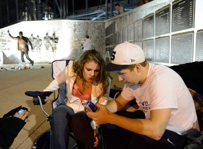 Penn State students Courtney Brenner, left and Mike Elliott of Lancaster, Pa. sit near the Joe Paterno statue early Sunday morning July 22, 2012. They said they were there to show their support for Paterno. The famed statue was taken down from outside the Penn State football stadium Sunday eliminating a key piece of the iconography surrounding the once-sainted football coach accused of burying child sex abuse allegations against a retired assistant. (AP Photo/John Beale)