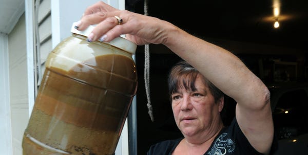 Joanne Barron shows a jug of water with oil in it that was pulled from her well in Emerald Lake.