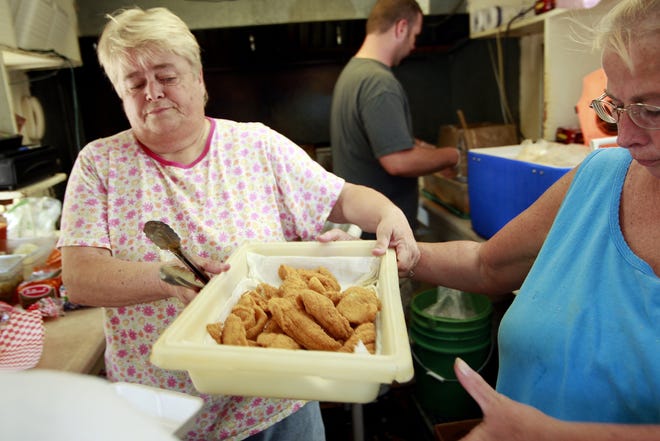 Rose Cole, right, hands Lynne Pryor a pan of walleye Friday as they rush to keep up with lunch orders at Carter’s Fish Market at 1900 South Grand Ave. E. Passing trains often cause traffic backups in front of the business.