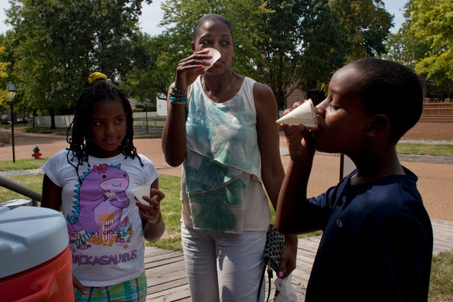 Kelleigh and Dexter Wakefield stop for a drink of cold water with their mother, Kelli, on Tuesday before taking a tour of the Lincoln Home National Historic Site. The National Park Service put the jug out to cool visitors.
