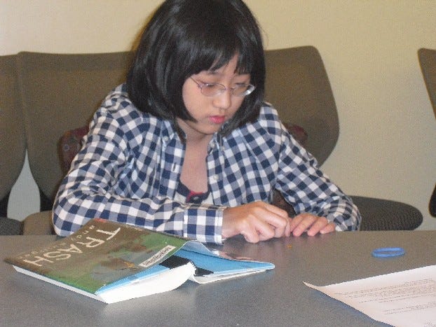 Bec Kim, 12, takes part in a discussion of ‘Trash’ by Andy Mulligan during a meeting of the Middle School Book Club at Cary Memorial Library on July 23.