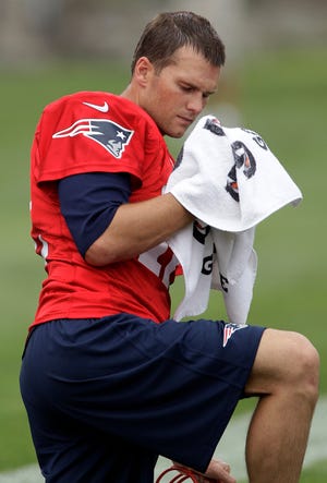 New England Patriots quarterback Tom Brady (12) wipes the sweat off his face during practice on the second day of training camp at the NFL football team's facility in Foxborough, Mass., Friday, July 27, 2012. (AP Photo/Stephan Savoia)