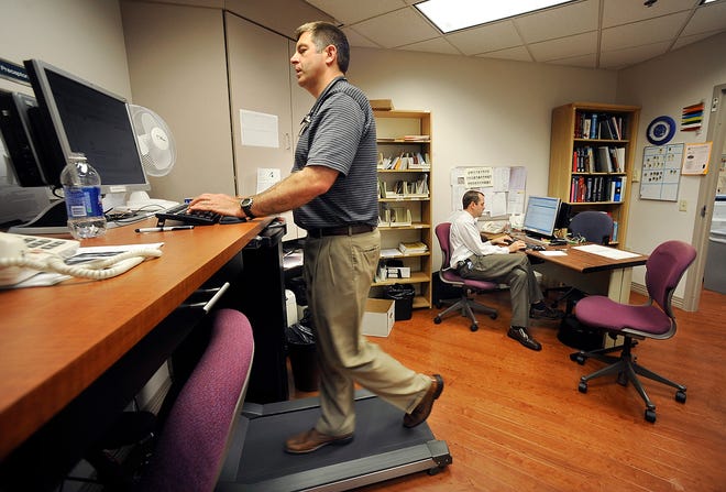 Dr. Jeff Leman, left, walks on a treadmill while working at a desk at Methodist Clinic as Dr. Marc Carrigan works seated at a desk. Leman and Carrigan are both faculty in the University of Illinois College of Medicine at Peoria and Methodist Medical Center family practice program. To combat the sedentary work of sitting at a desk and reviewing patient files, the clinic has installed a treadmill offering the opportunity for exercise.