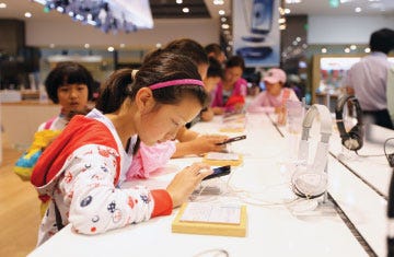 Children try out Galaxy smartphones Friday at a Samsung showroom in Seoul, South Korea. Samsung sold an estimated 50 million smartphones in the second quarter, double the market share of rival Apple. (AP PHOTO/HYE SOO NAH)