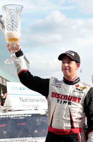 Brad Keselowski holds up the trophy into which he had poured beer, after winning the NASCAR Nationwide Series auto race at Indianapolis Motor Speedway in Indianapolis, Saturday, July 28, 2012. (AP Photo/AJ Mast)