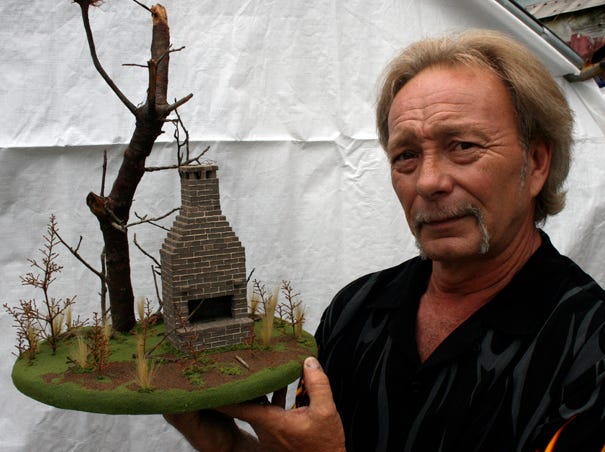 Eric Skipper, a model-maker for films, poses with one of his creations, the remains of an old house.