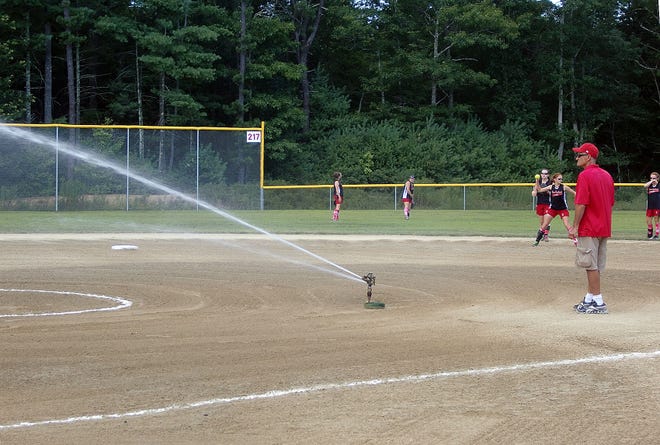 Kingston Youth Sports Organization president Jack Riordan, a coach of the 14U Kingston Kannons, helps spray down the field between games at this weekend's Kingston Invitational softball tournament hosted by the Kingston Youth Baseball and Softball League.