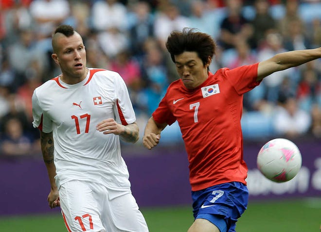 South Korea's Kim Bok-yung, right, battles for the ball against Switzerland's Michel Morganella during their Olympic soccer match. The Swiss team expelled Morganella for a racist and threatening tweet.