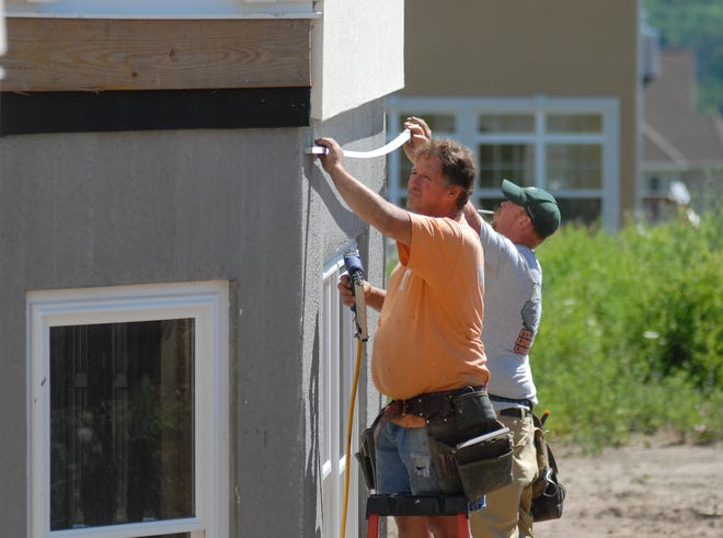 (left to right) Lincoln Franchell and Steve Worden of Rich Home Building & Development, instal exterior trim during the construction of a new home, July 25, 2012, in New Hartford, N.Y.