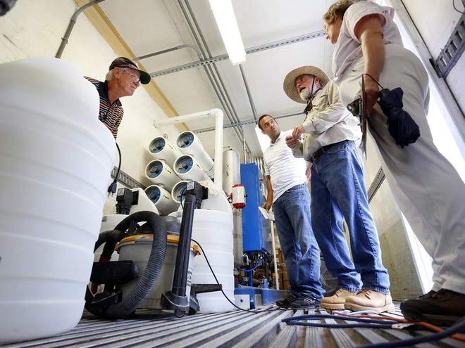 Blanche E.A. Waller of the Florida Department of Environmental Protection, right to left, David Beach, chairman of the Cedar Key Water and Sewer District, Arturo Aranda of the DEP, and Harry Kaufmann, an engineer with Mittauer & Associates, inspect the new reverse osmosis plants installed to clean the municipal water Monday after saltwater fouled the wells in Cedar Key.