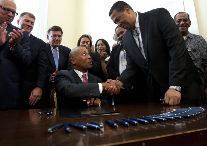 Massachusetts Gov. Deval Patrick, center, shakes hands with Cedric Cromwell, chairman of the Mashpee Wampanoag tribe, right, moments after Patrick signed a casino compact bill during ceremonies at the Statehouse, in Boston, Monday, July 30, 2012. The agreement, negotiated by the administration and ratified by the Legislature, will grant the tribe exclusive rights to develop a resort casino in southeastern Massachusetts. (AP Photo/Steven Senne)