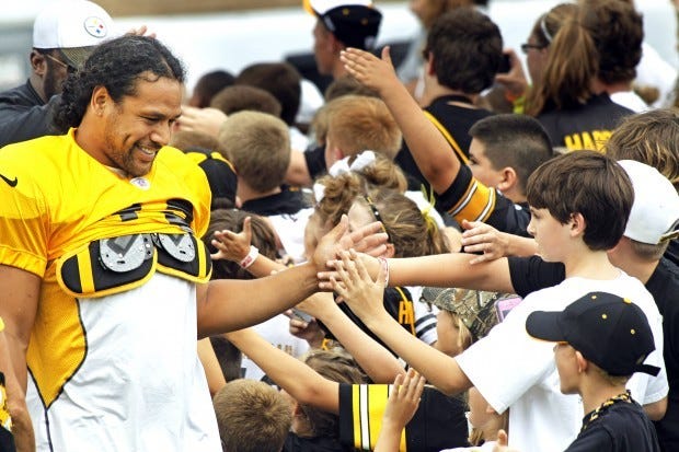 Pittsburgh Steelers defensive back Troy Polamalu, left, greets kids from the Pittsburgh Steelers Kids Club on the practice fields at NFL football training camp in Latrobe, Pa., Tuesday, July 31, 2012. (AP Photo/Keith Srakocic)