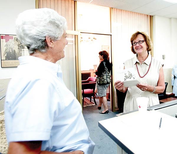 Photo by Amy Herzog/New Jersey Herald - Patricia Day, executive director of the Sussex County Chapter of the Red Cross, right, who is retiring after 23 years of service, opens a card from Chris Mayes, left, during an open house to say goodbye to Day.
