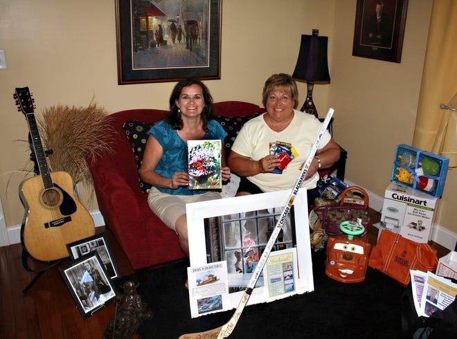 Laura Ramseyer, left, and Cindy Renzelman show examples of some of the items that will be auctioned, including a signed Chicago Blackhawk's hockey stick, above, and a handful of older, more valuable comic books, at right, that will be auctioned off to raise money for the band program at District #429.