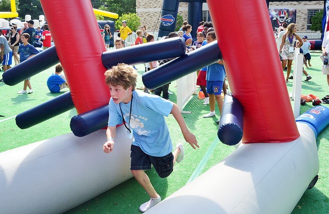Alex Winterberger, 12, of Brighton, blasts through one of the blow up displays at Bills Camp on Thursday as part of a group from Camp Good Days and Special Times that attended the camp at St. John Fisher College.