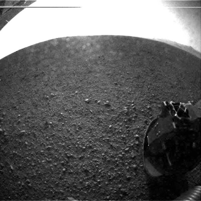 This photo provided by NASA's Jet Propulsion Laboratory shows the gravel on the surface of Mars' Gale Crater where the Curiosity rover landed late Sunday. On the horizon is the rim of the crater. Part of the spring that released the lens' dust cover can be seen at the bottom right, near the rover's wheel. At top left is part of the rover's power supply.