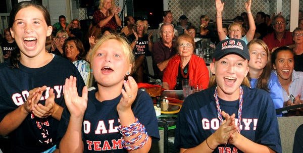 Anna Horgan, 12, far left, Lauren Cloherty, 9, and Rachael Moore, 15, all of Falmouth, cheer for their neighbor Aly Raisman on Tuesday night at the Courtyard Restaurant & Pub in Cataumet.