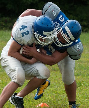 South Davidson’s Michael Rebello (right) wraps up teammate Chase Parks during a tackling drill at practice Tuesday afternoon.