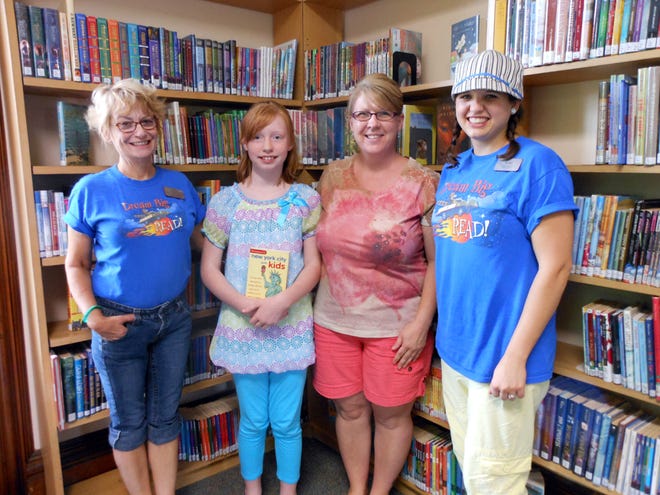Hailey Zimmerman, 9, stands with Ionia Community Library children’s librarian Melissa McAlvey (right), teen librarian Sally Wilcox (left) and her mother Wendy Zimmerman Wednesday after learning she has won a trip to New York City for four, sponsored by WoodTV. Zimmerman beat out about 65,000 other children involved in regional summer reading programs.