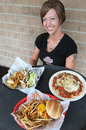 Tara Felton, a server at The Basement, holds a tray with gyro and chips, the Monday special, a half-pound burger and chips which is the Tuesday special, and the Thursday special, Chicken Parmesan.