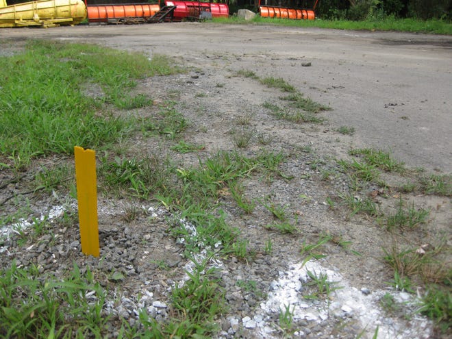 A test hole used to determine the contaminants contained in the area behind the Dighton Highway garage. The contaminated area begins at this hole and runs roughly to the property line marked with plows.