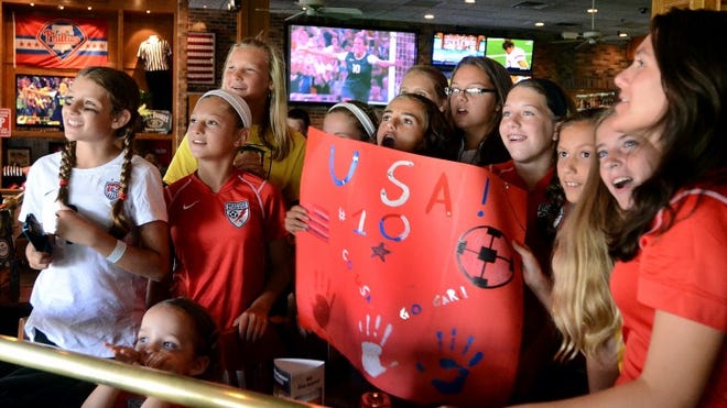 Members of the Medford Strikers and Universal Soccer Academy in Medford react as (on the TV screen in the background ) Carli Lloyd scored her second goal in the gold medal game in Women's Soccer in the 2012 London Olympics as they viewed the game at Champps in Evesham.