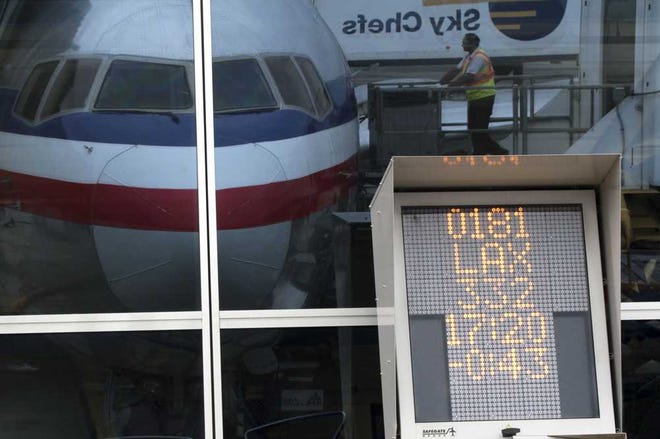 Associated Press A countdown to departure clock is framed by a reflection of an American Airlines fleet clerk servicing an airplane on Aug. 1 at New York's JFK International Airport.