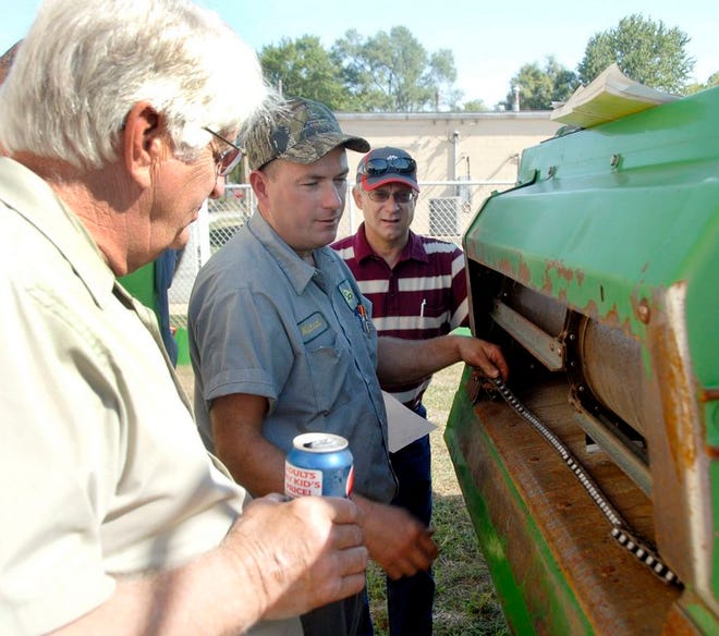 Outside, farmers with older equipment talked with Michael Graf, a combine technician for Kelly, Sauder and Rupiper Equipment about maintenance on some of the older combine models. Graf used a John Deere 9510 combine for his instructions. From left are Jim Drach, Graf and Nick Eggenberger.