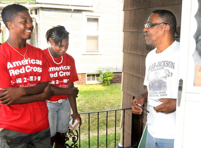Hartford Middle School 8th graders Jaron Lee, left, and Jalea Jones, center, chat with Gregory Burnett, a resident on 3rd Street who recieved one of the smoke detectors Hartford students delivered to the neighborhood Thursday.