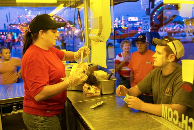 Shelly Newton serves up a buca-wich to Dylan Gnade on Friday at the Illinois State Fair. The buca-wich is a 6-inch hoagie with the center removed and filled with either crawfish (with peppers and onions), Cajun steak, meatballs, Italian sausage, peanut butter and jelly, tuna salad or chicken salad.