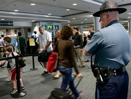 FILE - In this Thursday, Aug. 10, 2006 file photo, a Massachusetts state trooper keeps watch over travelers making their way through Logan International Airport in Boston. Transportation Security Administration officers at Boston's Logan International Airport are alleging that a program intended to help flag possible terrorists based on passengers' mannerisms has led to rampant racial profiling, the New York Times reported Saturday, Aug. 11,2012.