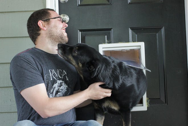 Ryan Hallock is licked by Zelda, a 4-year-old Rottweiler mix, who uses the doggy door at her home in Covington, Wash.