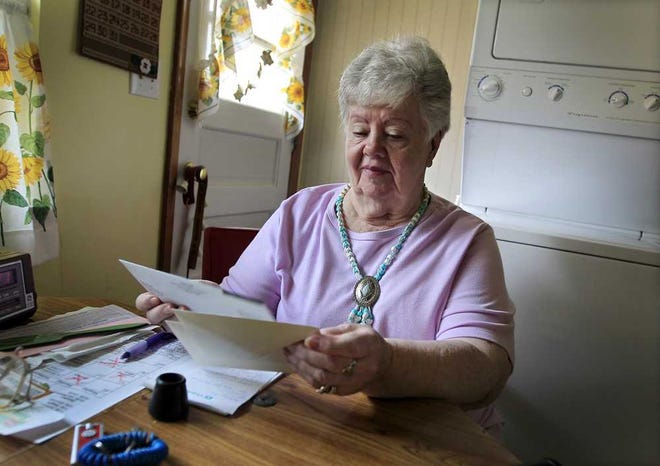 Neta Homier looks over bills in her home in Toledo, Ohio. Homier says she started receiving Social Security when she was 63 and now gets about $800 a month, after her Medicare premiums are deducted.