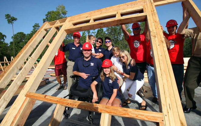Marine Gunnery Sgt. John Hayes, his family and Tyler and Ashley Southern are framed by a window in the first wall to be raised by Home For Our Troops on Friday morning, August 10, 2012. Hayes was on his 4th deployment when he lost both of his legs after stepping on an IED in Sangin, Afganistan. BY DARON DEAN, daron.dean@staugustine.com