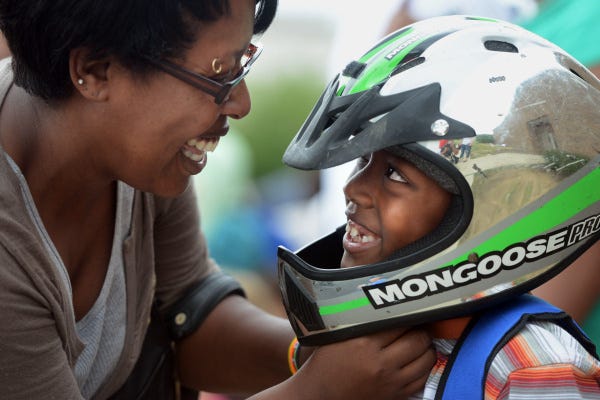 Robin Watson of Columbus tightens the helmet straps for her 6-year-old son, Emmanuel, as he prepares for his first ride on a motorcycle during the Single Parent Fun Day on Sunday at the Grove City Church of the Nazarene. More than 1,600 people took part in the daylong event, dedicated to single parents. The festivities featured face-painting, motorcycle rides, games and live entertainment. The families who participated received backpacks with school supplies and were treated to a picnic lunch to end the day.