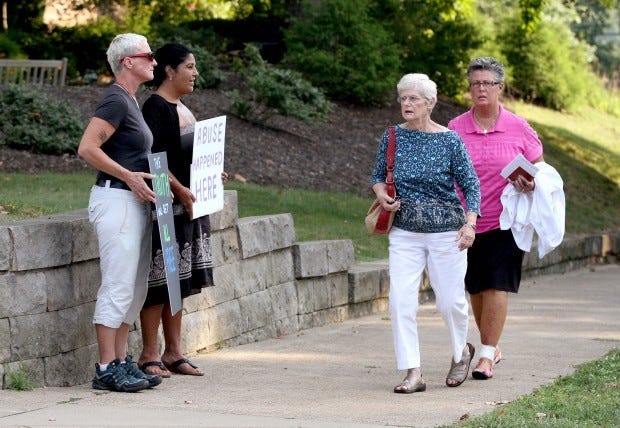 Protesters Lynn X. Wilkinson, far left, of Wexford and Mary Persuit, of Sewickley hold signs reading, "the truth will set all free" and "abuse happened here" as parishioners walk to St.James Church on Walnut Street in Sewickley on Wednesday. The Rev. Daniel Valentine stepped down after controversial communication with an adolescent on Facebook.